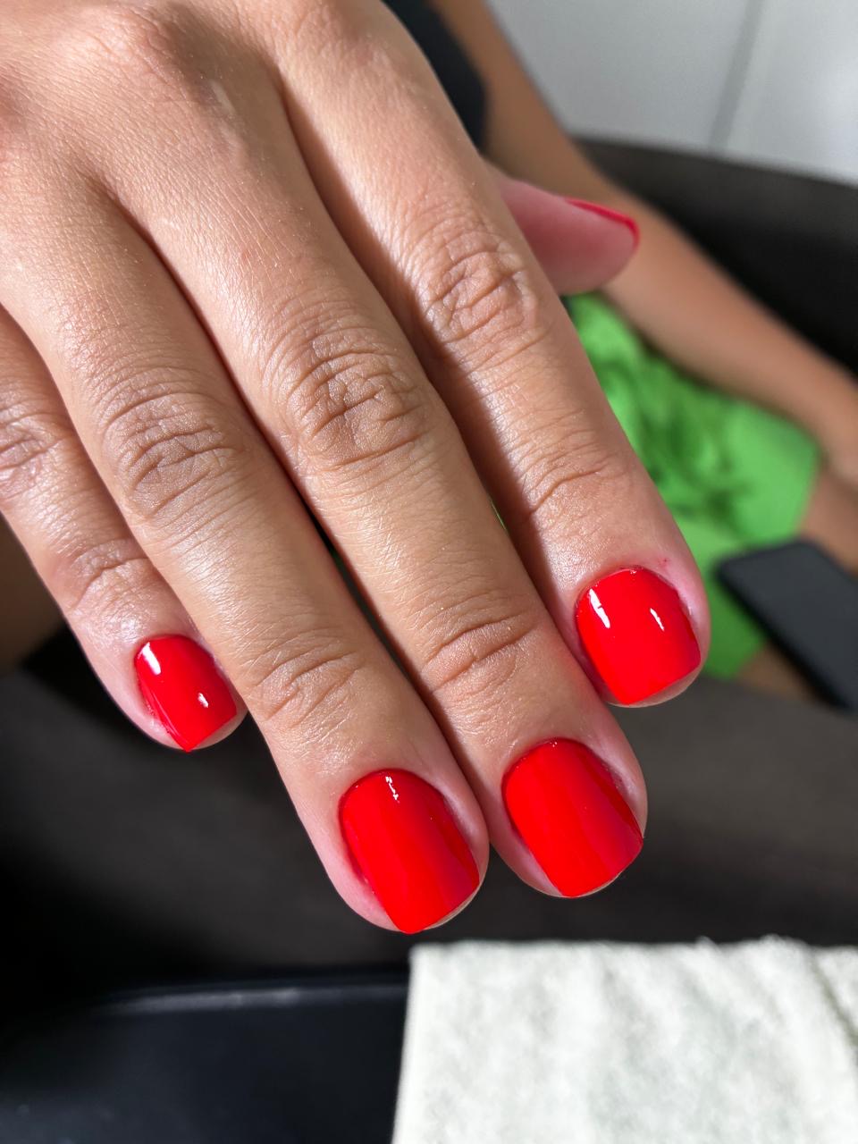 Unhas esmaltadas em vermelho vibrante